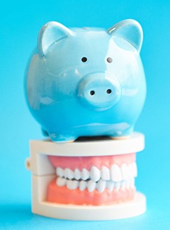 Piggy bank and teeth representing cost of dental implants in Topeka