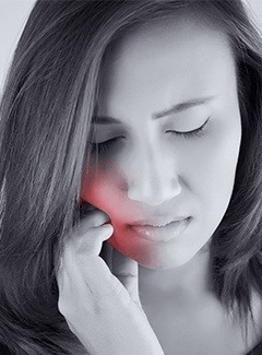 Woman with hand on cheek because of tooth pain