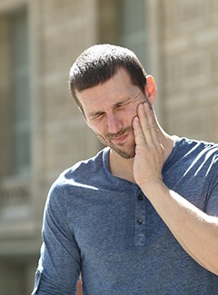 Man in blue shirt suffering from TMJ pain