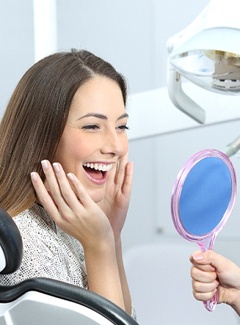 Woman admiring her new dental crowns in Topeka and Silver Lake