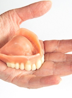 Hand holding full dentures in Topeka & Silver Lake, KS