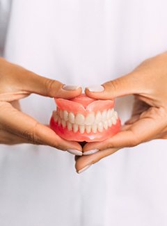 dentist holding dentures in hand