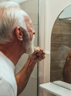 Man cleaning his dental implants in Topeka & Silver Lake