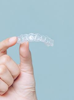 Closeup of smiling patient putting on clear aligner