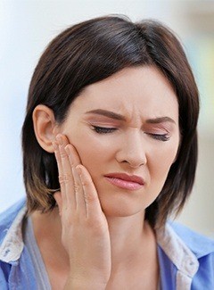 woman holding hand on face