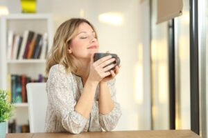 Woman smiling and holding a warm cup of coffee in her hands