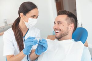 Man smiling at his dentist who is holding an Invisalign aligner