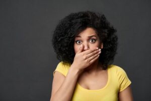 Shocked woman covering her mouth after her dental bridge fell out