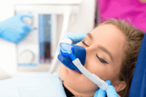Woman looking peaceful as dentist administers laughing gas